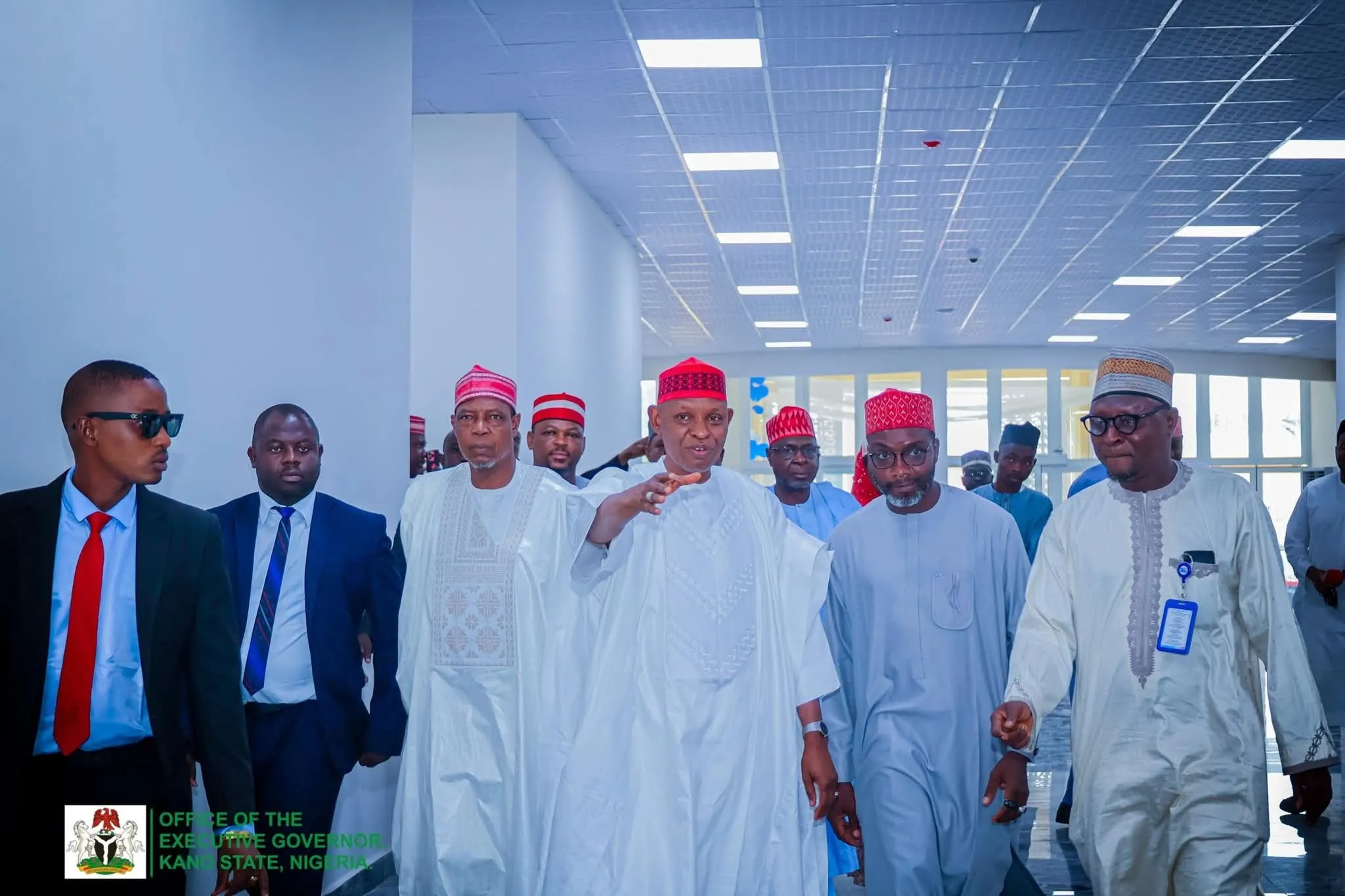 Kano State officials walking through the concourse of a newly completed public building.